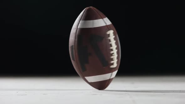 American Football Rotates Against Black Background Close Up