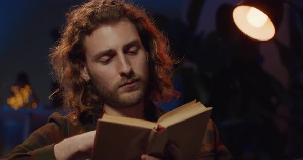 Close Up View of Inteligent Millennial Man Reading in Lamp Light While Looking Sleepy, Handsome Man