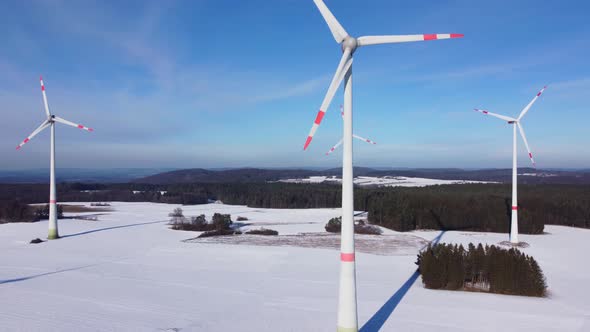 Bottom up aerial view of a wind farm. Rotating wind power plants in a winter landscape.