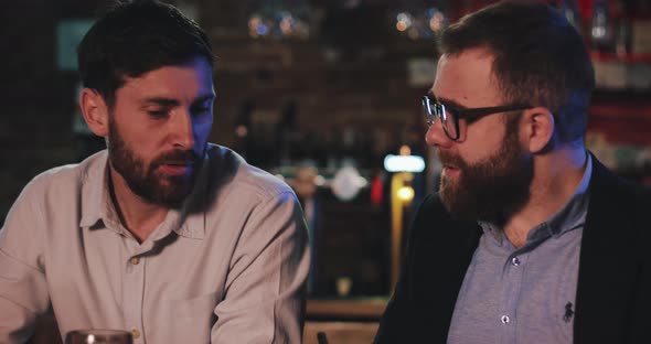 Close Up of Cheerful Male Friends Having Conversation While Drinking Beer in Pub