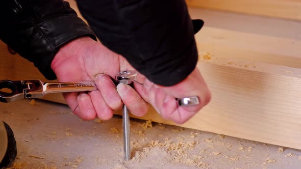 Hands of master twist washer with nut onto a threaded steel stud into concrete floor of rough floor