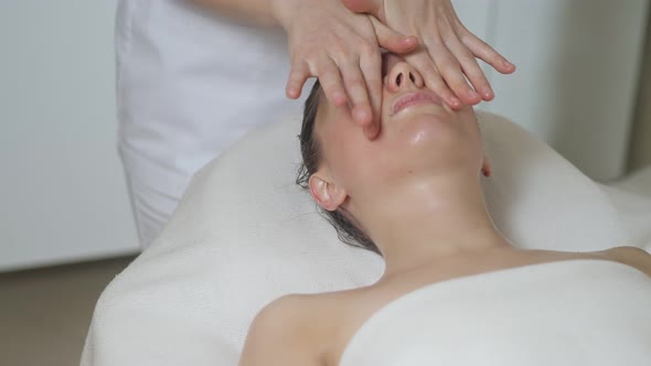 Cute Brunette Woman on Face Massage in Spa Salon