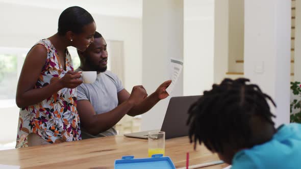 African american couple calculating finance and using computer at home