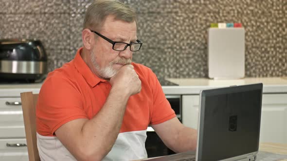 An Elderly Man Sits in Front of a Laptop