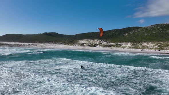 Person kitesurfing on dangerous powerful waves and jumps high in the sky