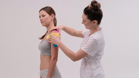 Therapist is applying kinesio tape to female body. Physiotherapy and kinesiology concepts.