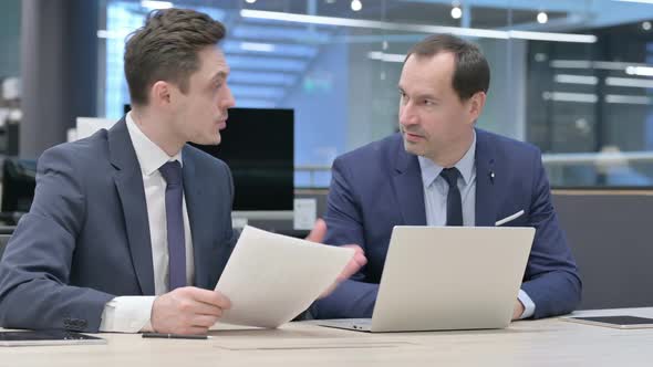 Two Businessman Discussing While Working on Laptop in Office