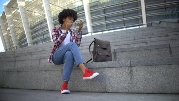 Attractive Curly Haired Student Looking in Hand Mirror, Enjoying Her Appearance