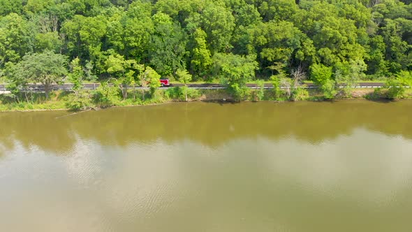 Drone right flight over a small country road in an Illinois forest preserve with lush green trees as