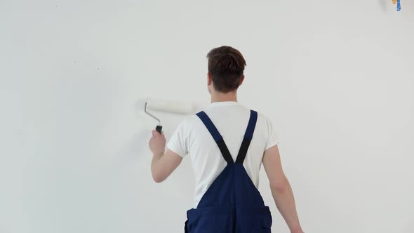 Painter with a Roller in His Hands Paints a White Wall