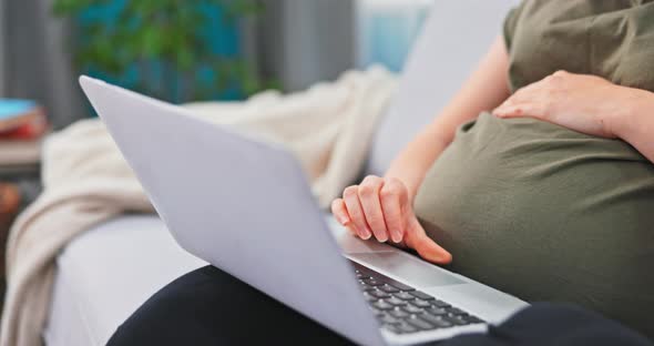 A Woman Dressed in Comfortable Clothes Relaxes on a Couch with a Laptop on Lap