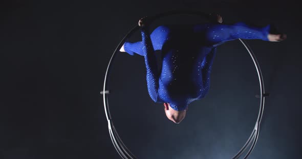 Woman in Blue Costume is Hanging Upside Down and Doing a Split in a Hoop