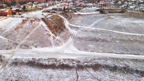 Field Slope and Village Under the Snow in the Orange Light of the Sun