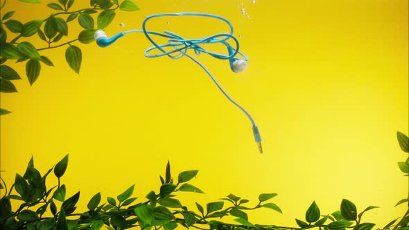 Sinking Blue Headphones in Water on Yellow Background Closeup Throwing Wired Earphones Into a River