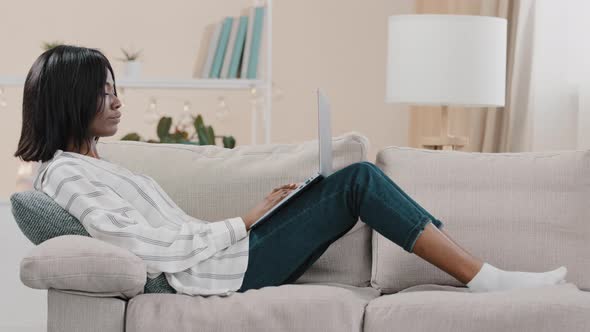 Young Woman Freelancer Student Lies on Comfortable Couch Typing on Laptop Working Studying Remote at