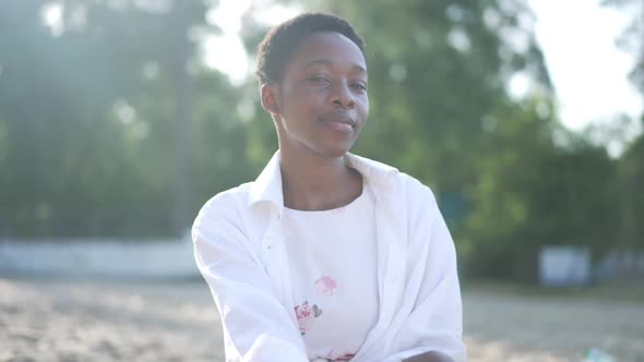 Live Camera Zoom Out As Confident Smiling African American Woman Sitting on Sandy Sunny Beach Posing