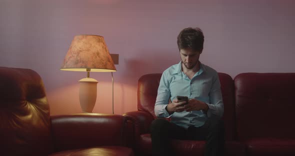 Guy lays the phone on the red sofa at home