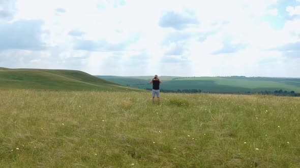 Aerial view of the traveler who walks through the fields in nature