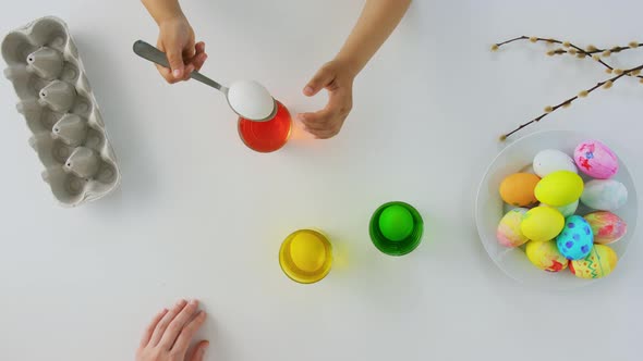 Hands of Child and Parent Dyeing Easter Eggs