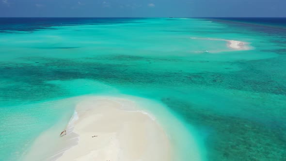 Wide angle drone travel shot of a white paradise beach and aqua blue water background in colourful 4
