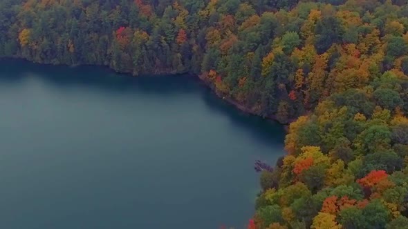 Gorgeous aerial shot of Pink Lake surrounded by the colorful forest of Gatineau Park.