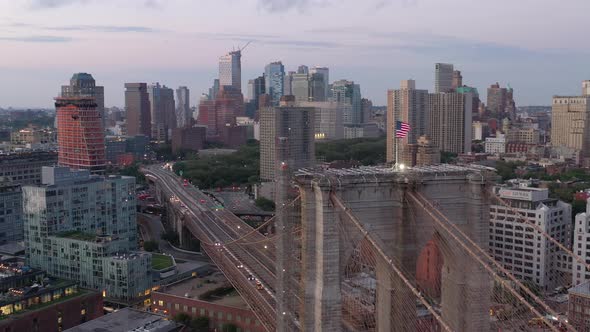 An aerial view of the Brooklyn Bridge at sunrise. The camera orbit the American flag on the bridge's