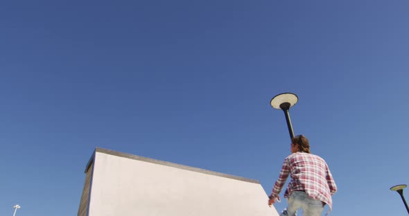 Caucasian man riding and jumping on skateboard on sunny day