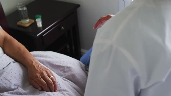 Close up of senior mixed race man with female doctor home visiting holding hands