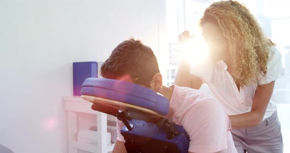 Female physiotherapist giving back massage to a male patient