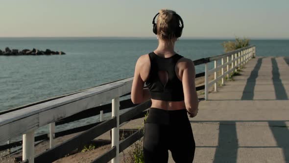 Young Athletic Woman Is Running and Jogging on Waterfront Near River, Back View.