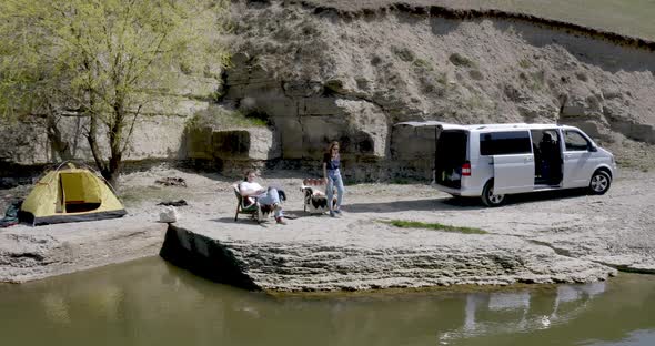 a guy and a girl are sitting on armchairs on the river bank camping tent rest