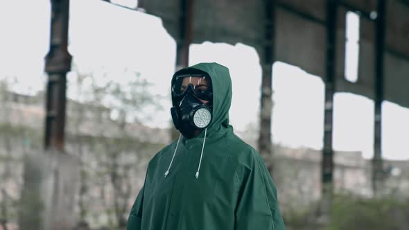 Man in gas mask and cloak for chemical protection on abandoned factory