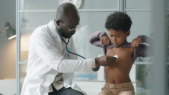 African American Doctor Giving Medical Checkup to Little Boy