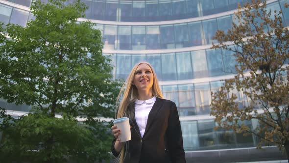 Stylish Business Woman with Coffee on Street. From Below of Serious Blond Executive Young Lady in