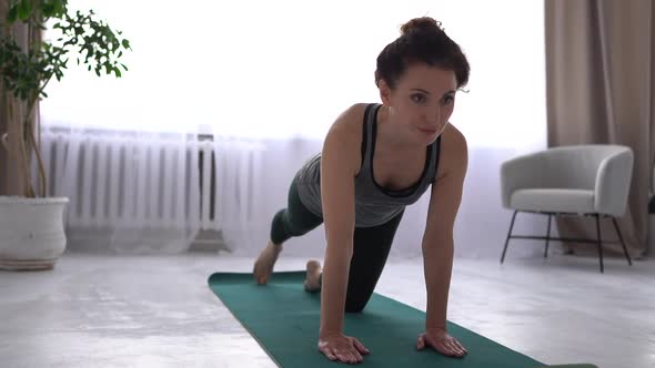 Beautiful Brunette is Working Out at Home on a Yoga Mat