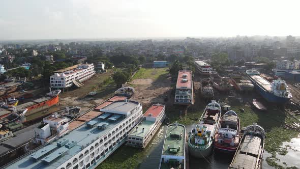 several ferries and steamer ships moored at dockyard on riverbank in Dhaka city, Bangladesh. aerial