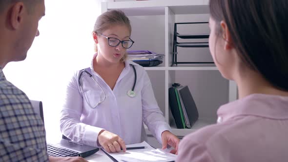 Doctor Female Talking About of Health with Couple in a Medical Office at a Fertility Clinic