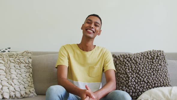 Happy mixed race man sitting on sofa laughing and talking