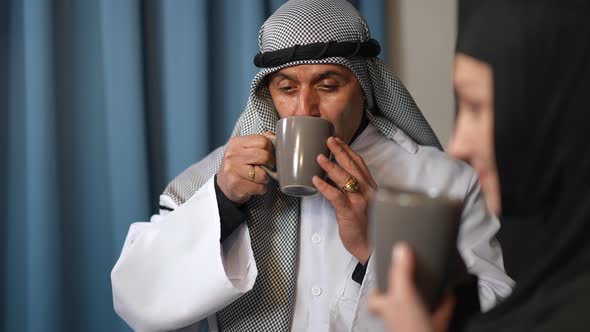 Portrait of Middle Eastern Husband Enjoying Taste of Morning Coffee Talking with Wife Smiling