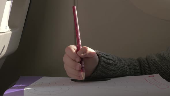 In Plane Sits a Little Boy and Draws with a Pencil on Paper