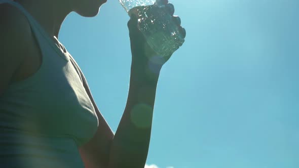 Sporty Woman Drinking Water Outdoor on Sunny Day