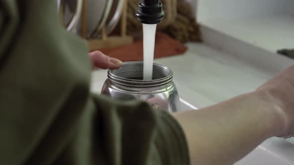 Woman make a coffee in moka pot in kitchen