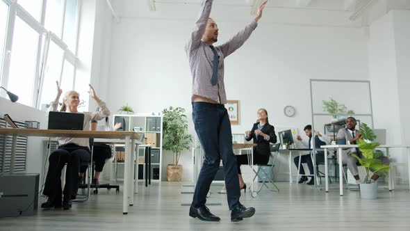 Creative Comic Performing Modern Dance in Office While Businesspeople Clapping Hands and Smiling