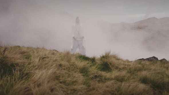 A Man Meditates on Top Of a Rock With Fog Surrounding Him