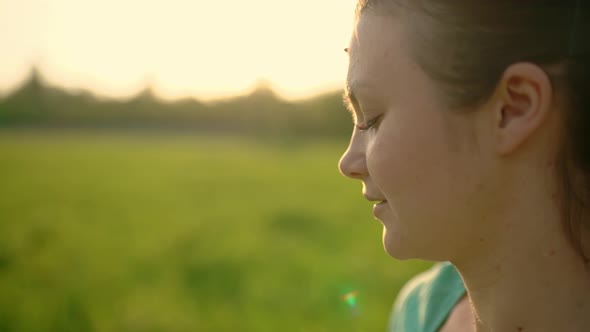 Closeup of a Young Happy Girl Blowing on a Dandelion