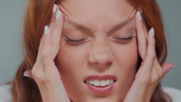 Tired Caucasian Woman Breathes Deeply and Massages Temples to Relax Closeup