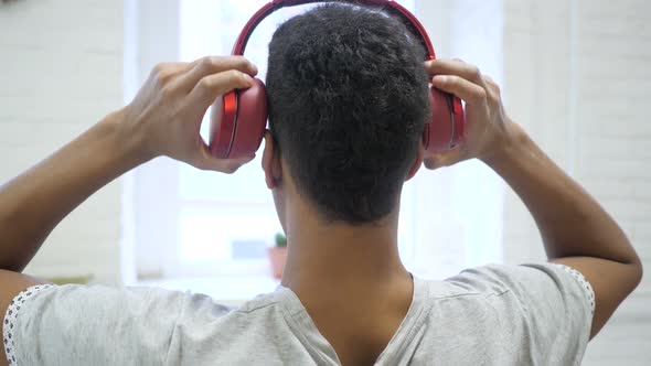 African Man Wearing Headphones for Listening, Back View