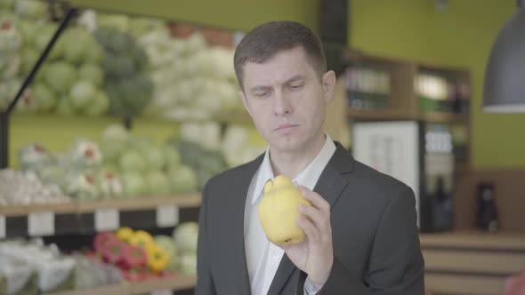 Young Caucasian Man Looking at Yellow Pear in Grocery and Showing Thumb Up. Confident Guy Choosing