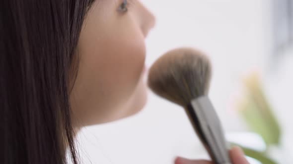 Young asian woman happy and smile with face looking mirror applying makeup with brusher of cheek.