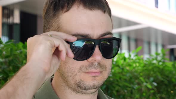 Man Looking at Camera From Under Black Sunglasses Showing Eye with Inflammation